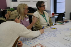 Participant recording discussion and ideas on paper tablecloth